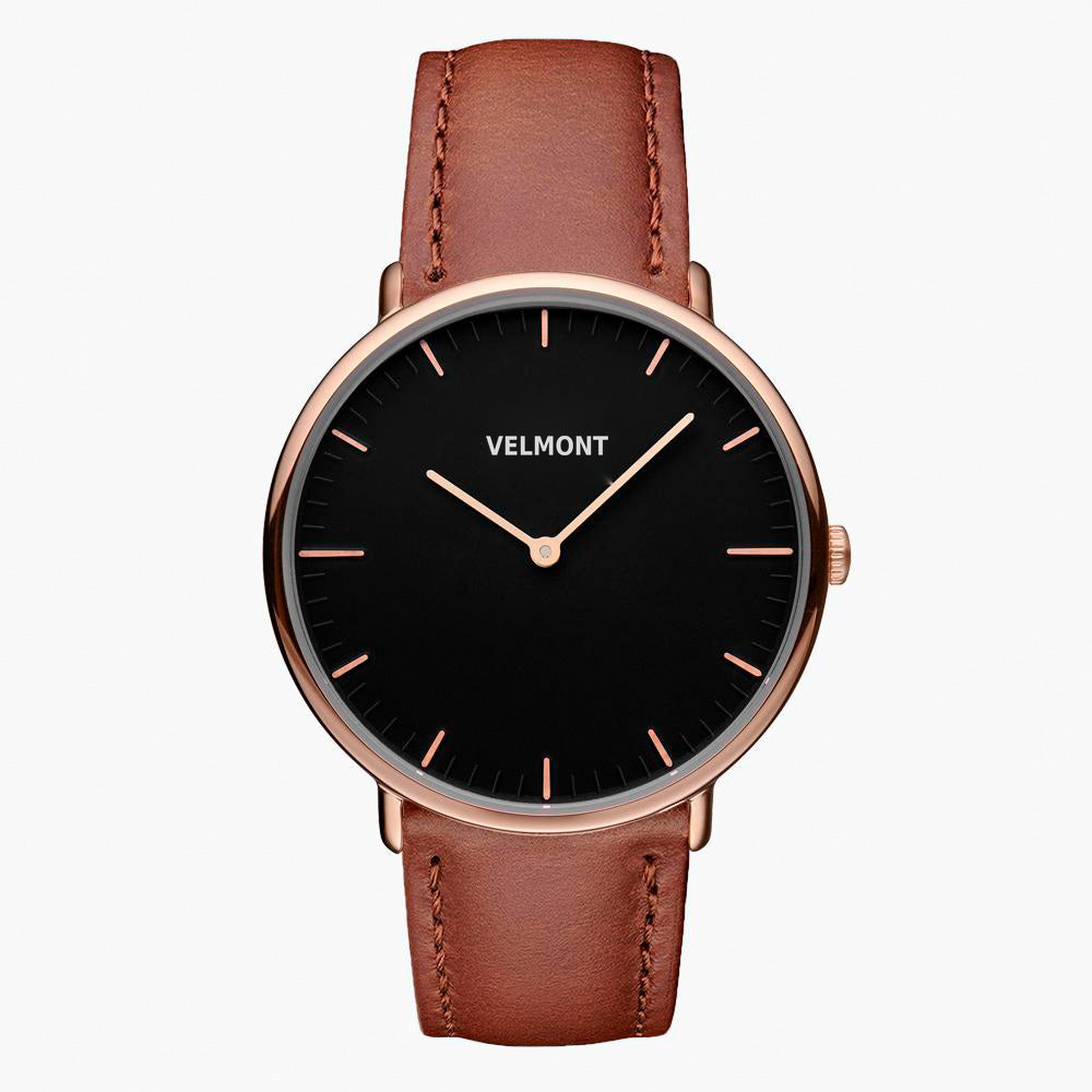 A black dial framed by a slim rose gold-tone case, set on a brown strap.