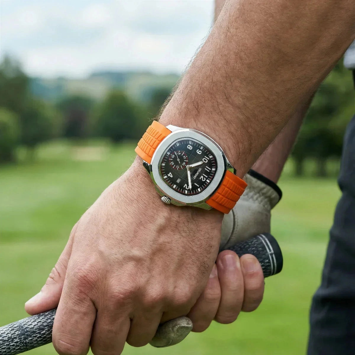 Orange-strap watch worn on a golf course