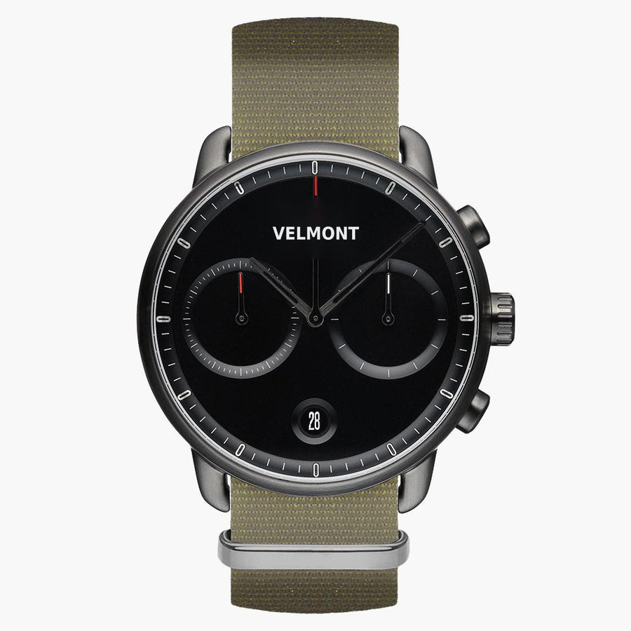 Chronograph-style watch with a black dial and gunmetal case on an olive woven strap.