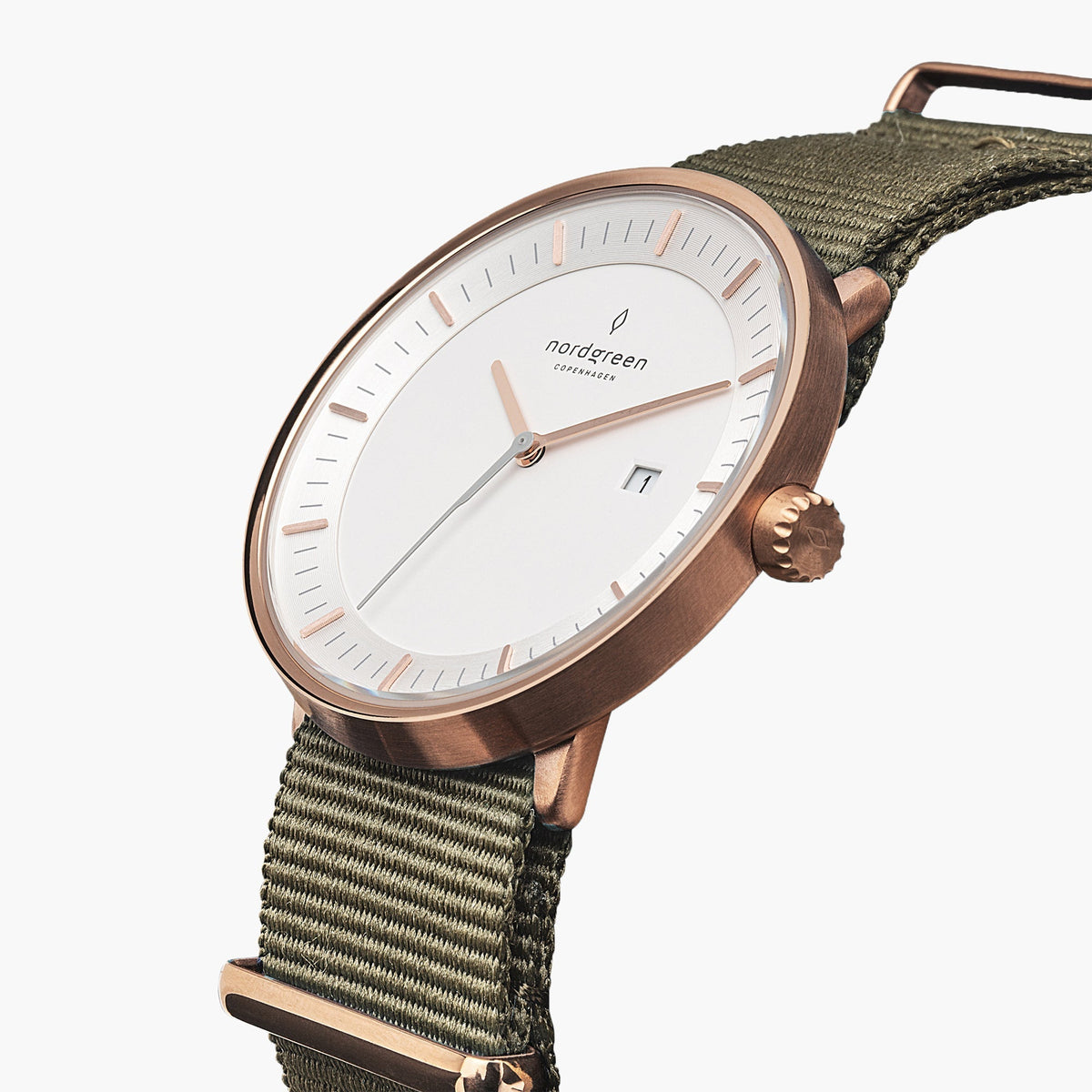 Three-quarter view of the rose gold-tone case and date window on a green woven strap.