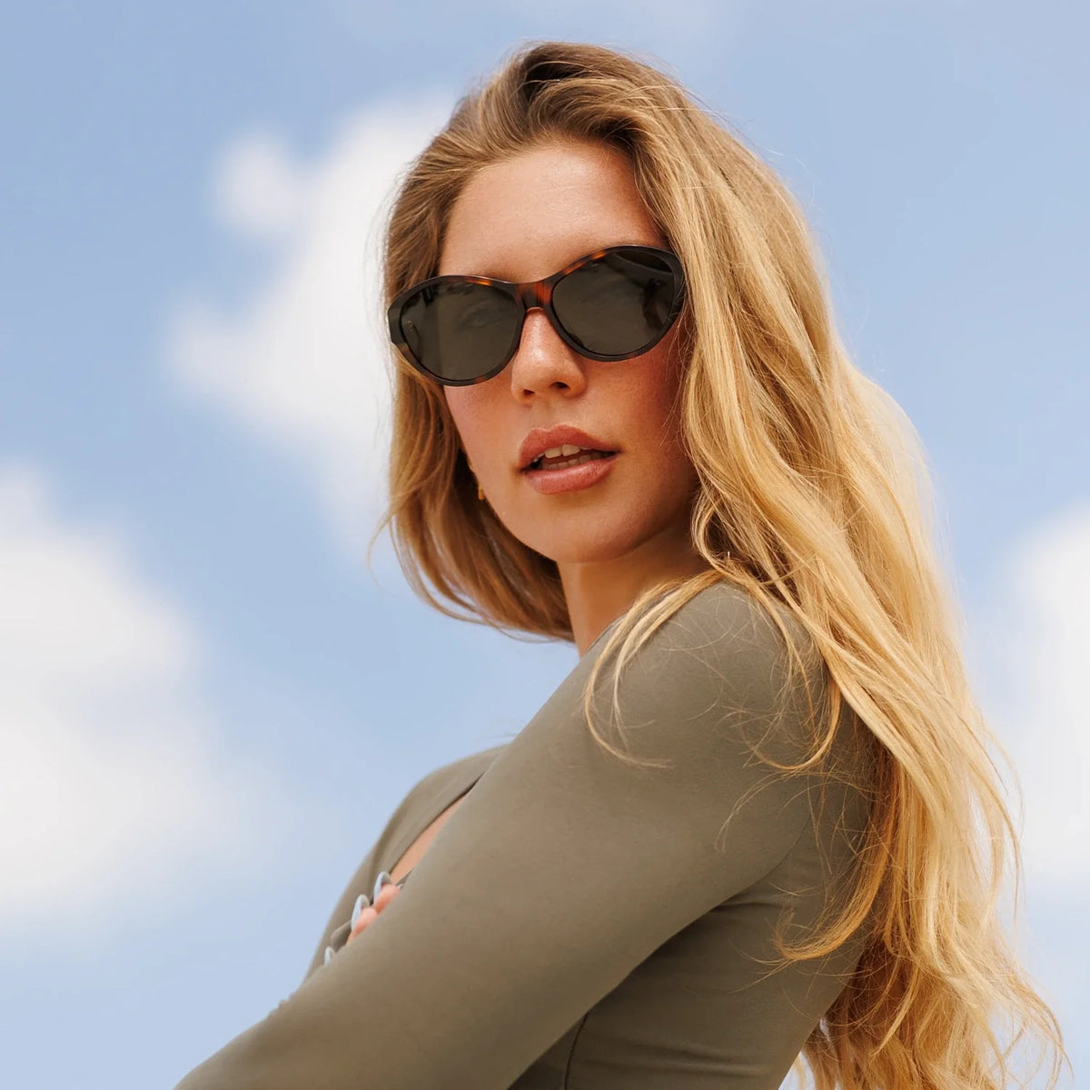 Woman in tortoise cat eye sunglasses against the sky