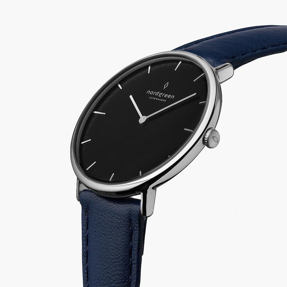 Three-quarter view of the slim silver-tone case and black dial on a navy strap.