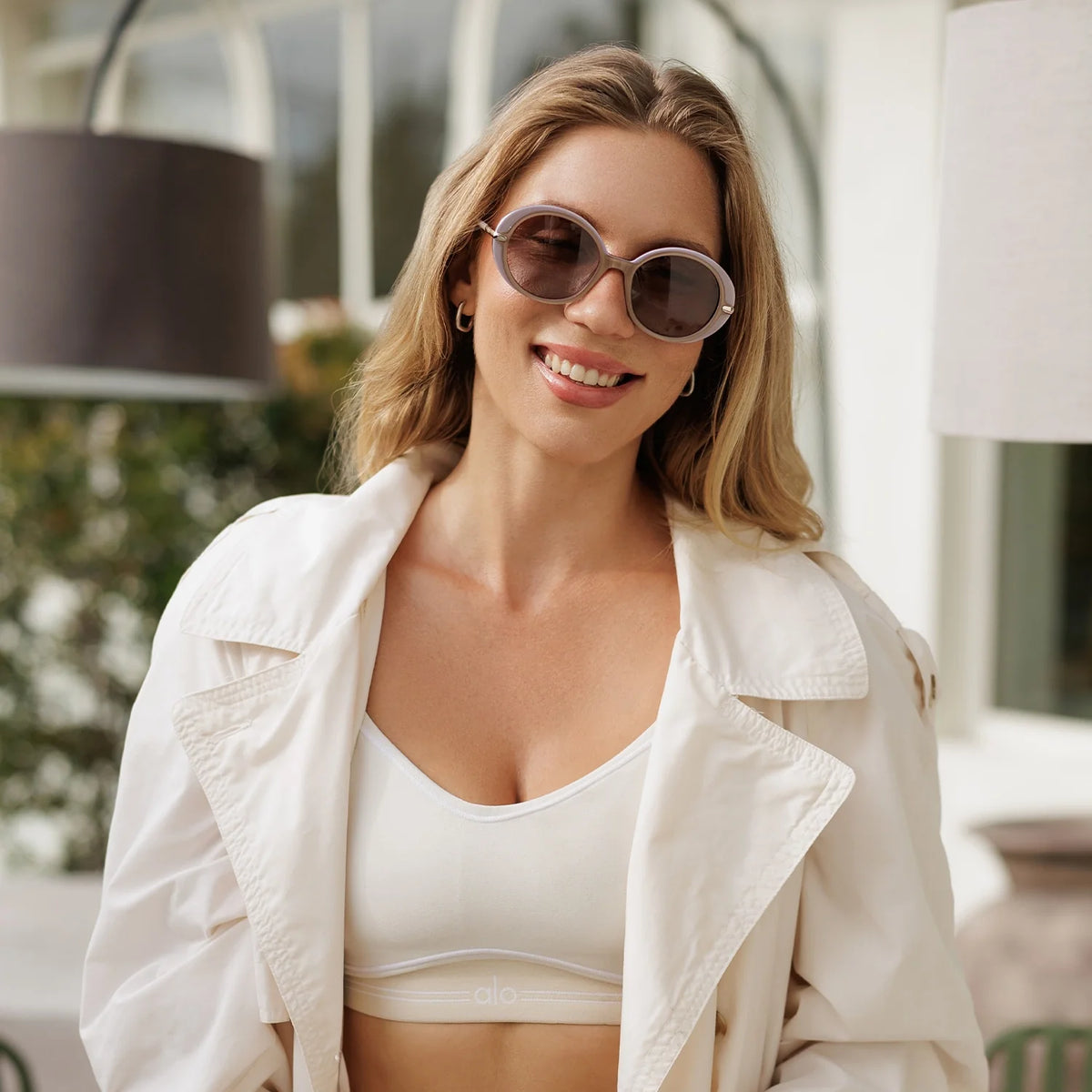 Woman in round sunglasses smiling outdoors