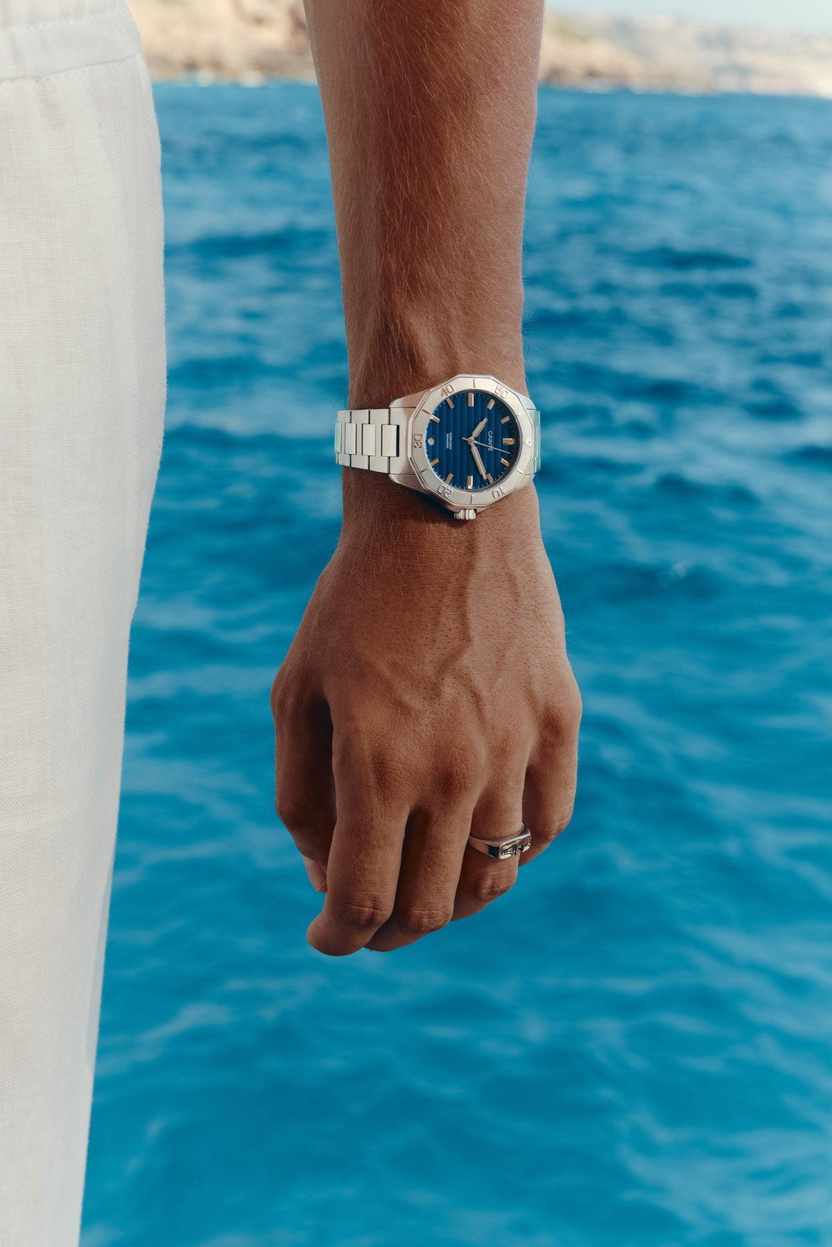 Watch with blue dial worn on the wrist above the sea