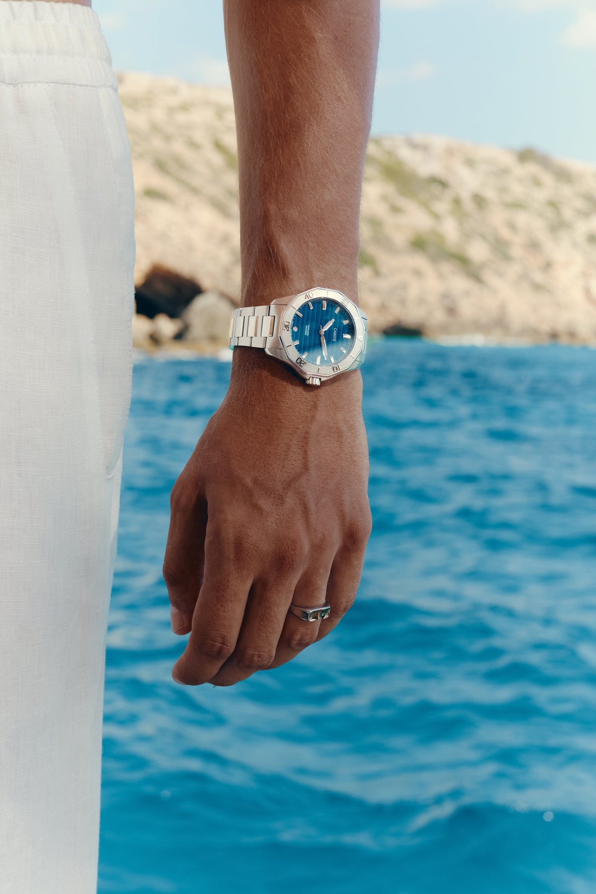 Watch with blue dial worn on the wrist above the sea