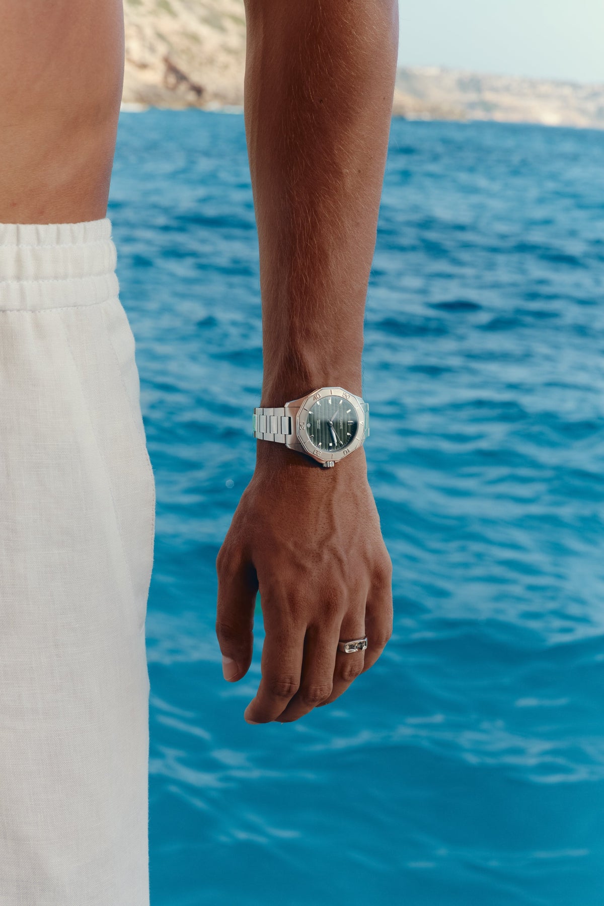 Watch with green dial worn on the wrist above the sea