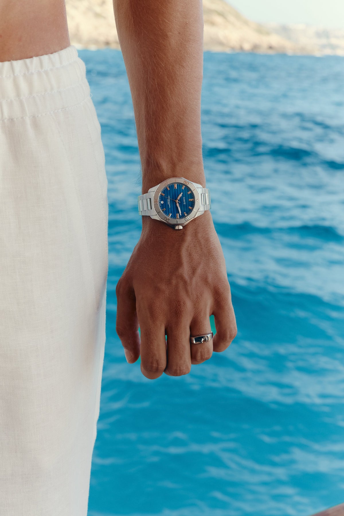 Watch with blue dial worn on the wrist above the sea