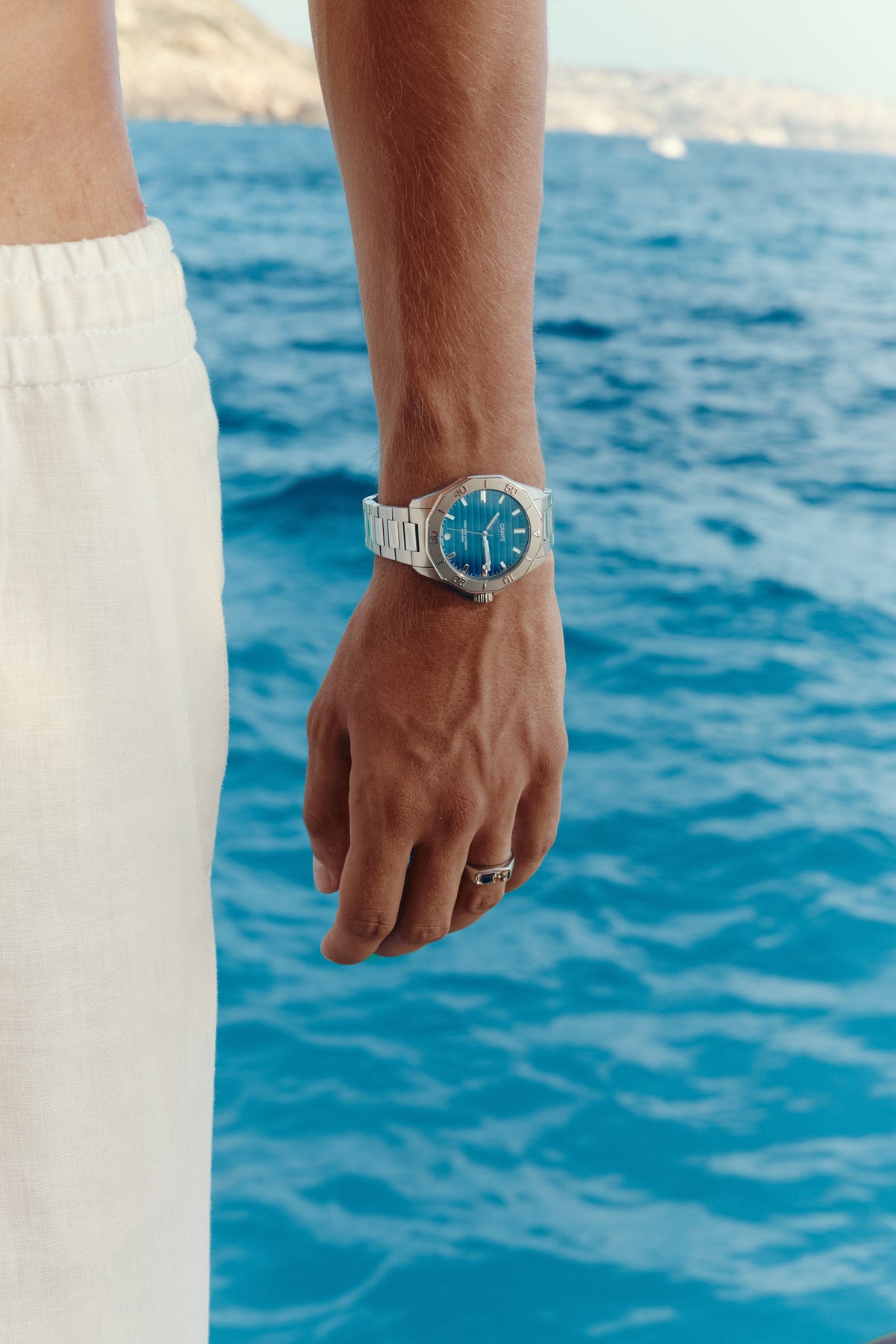 Close-up of the watch on the wrist, sea in the background