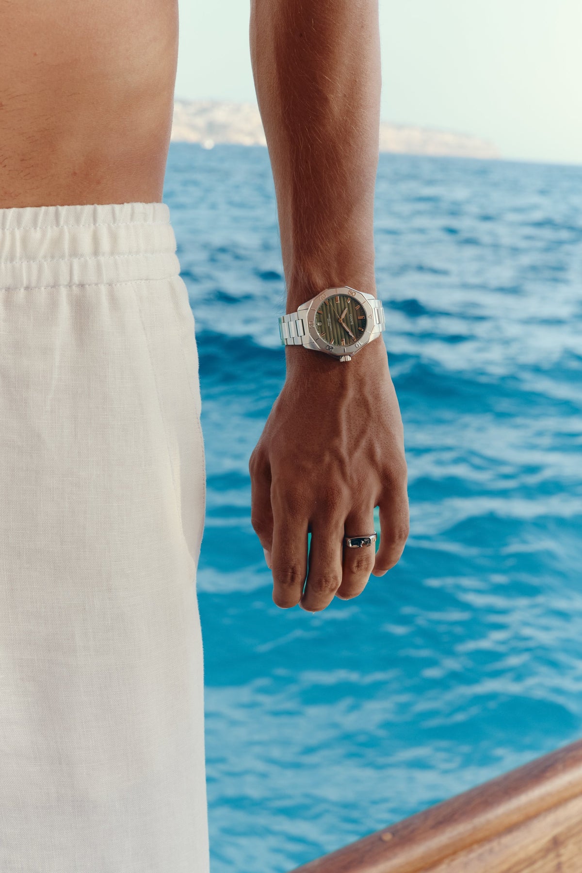 Green-dial automatic watch on the wrist, side view over the water