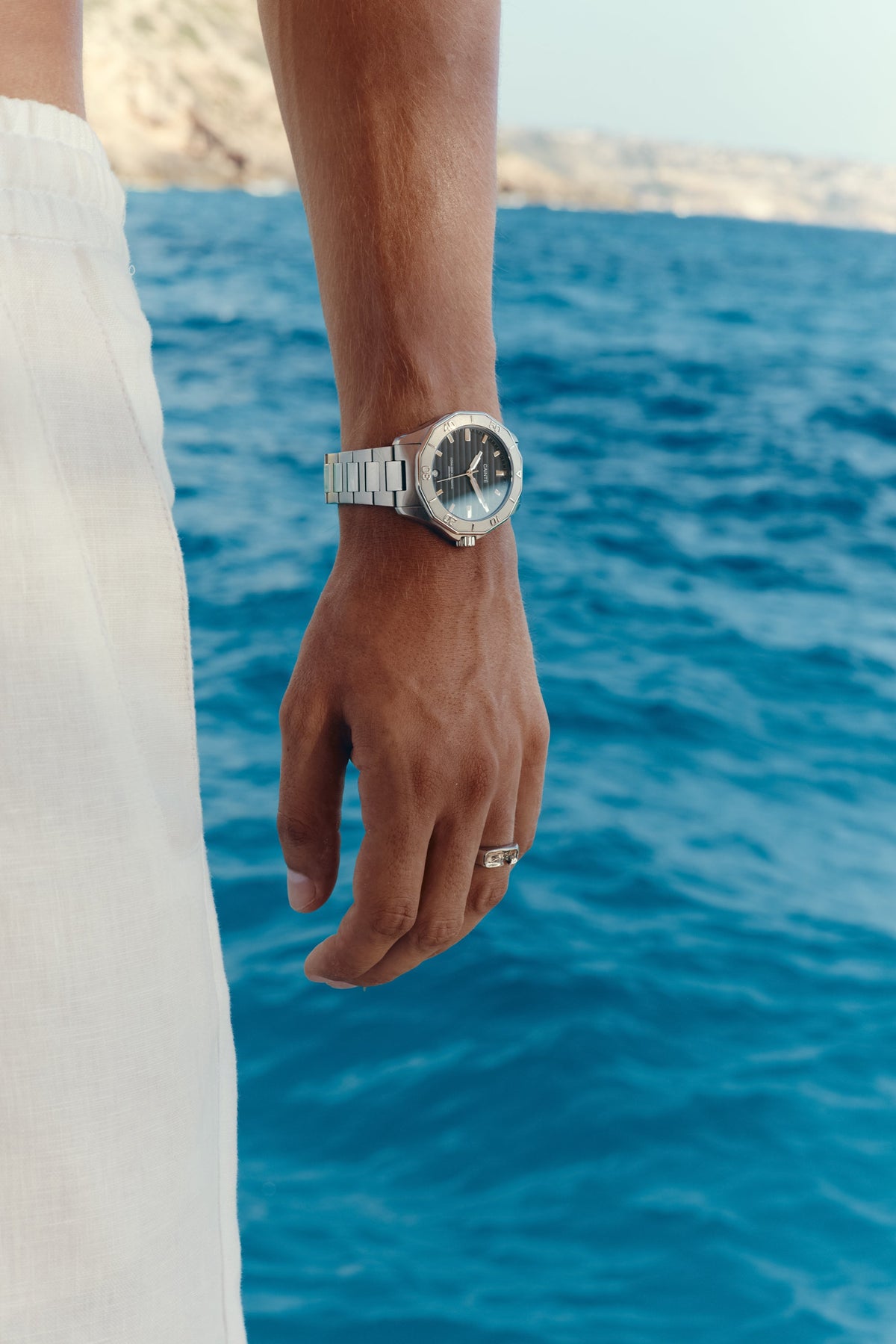 Hand by the water wearing the black-dial watch