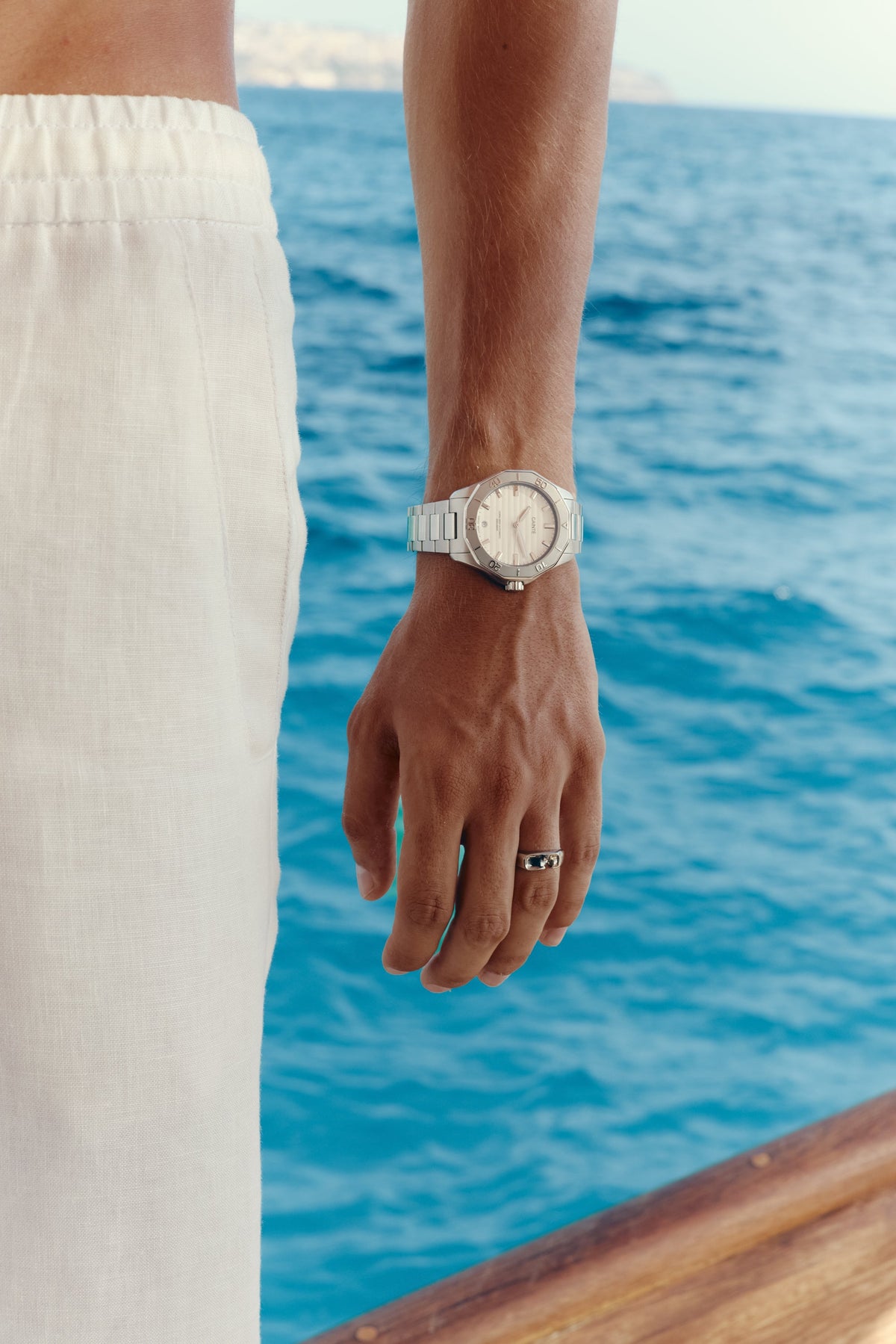 Hand by the water wearing the white-dial watch