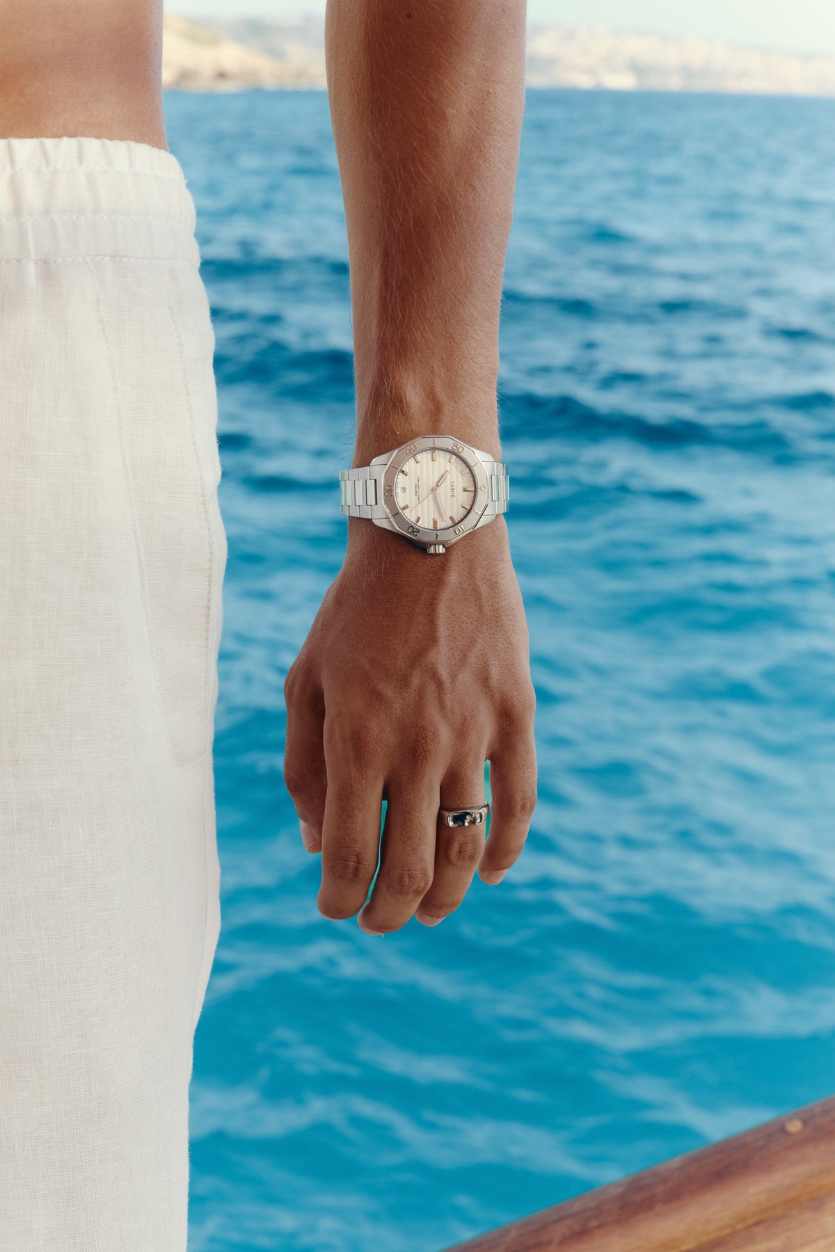Watch with white dial worn on the wrist above the sea