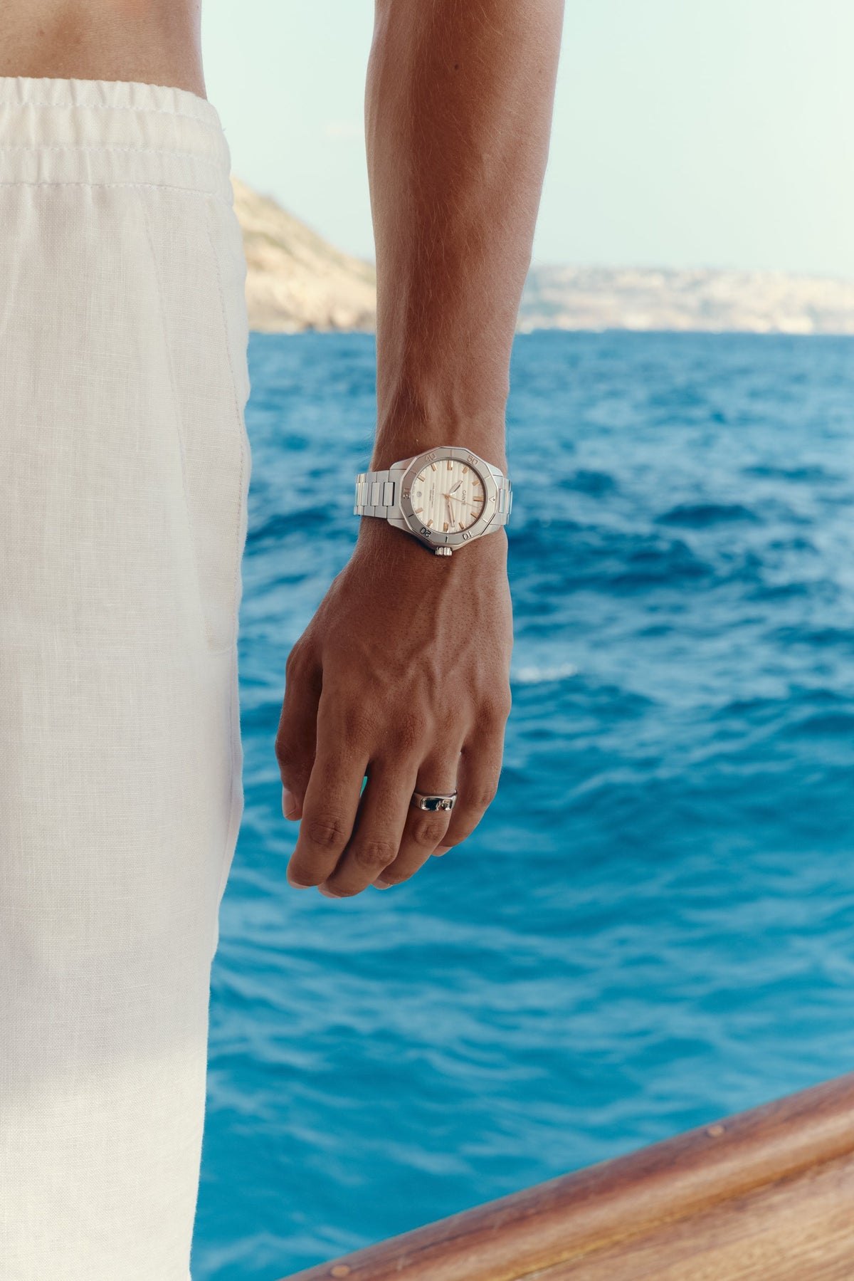 Watch with white dial worn on the wrist above the sea