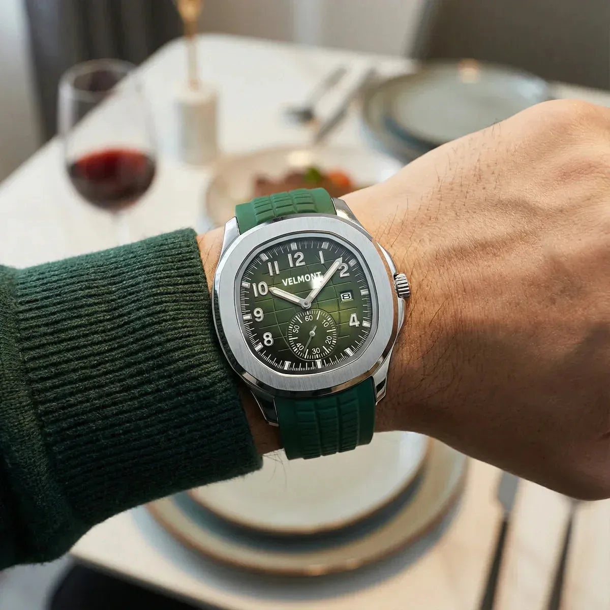 Green-dial watch with green rubber strap worn at a dinner table