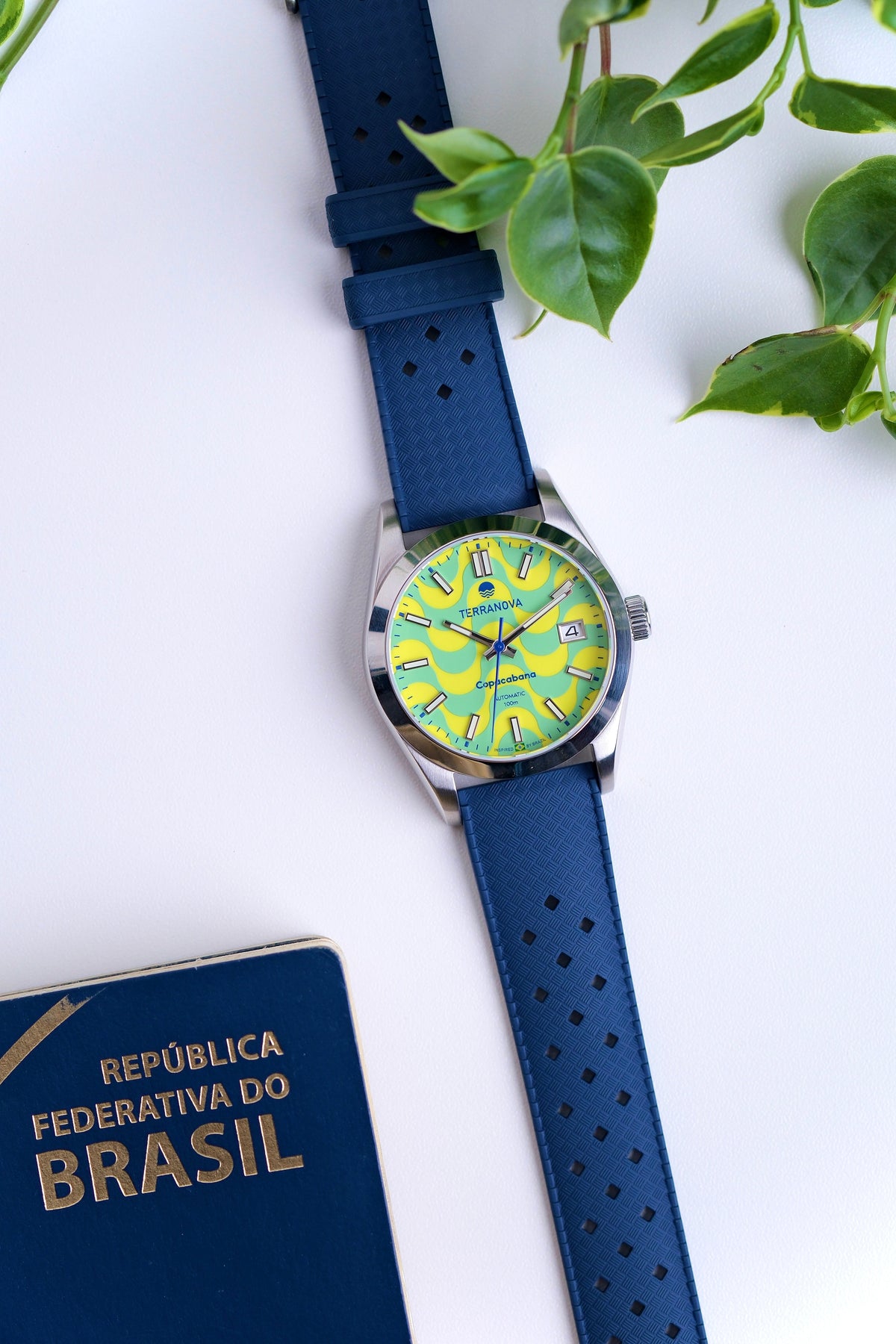Wave dial watch on a blue strap beside a passport