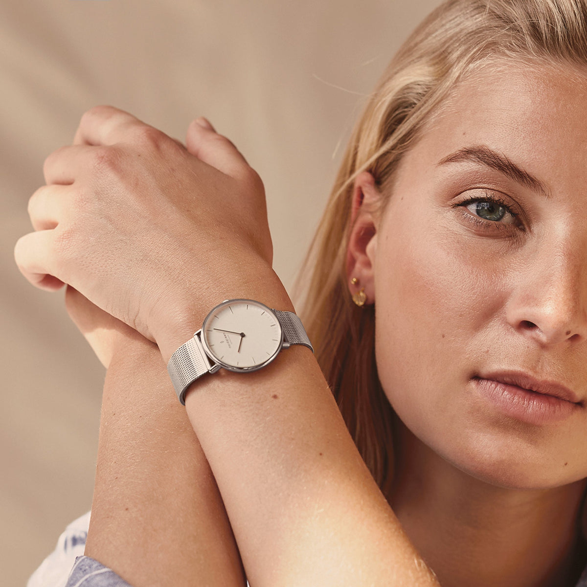 A woman with crossed arms wearing the silver-tone mesh watch.