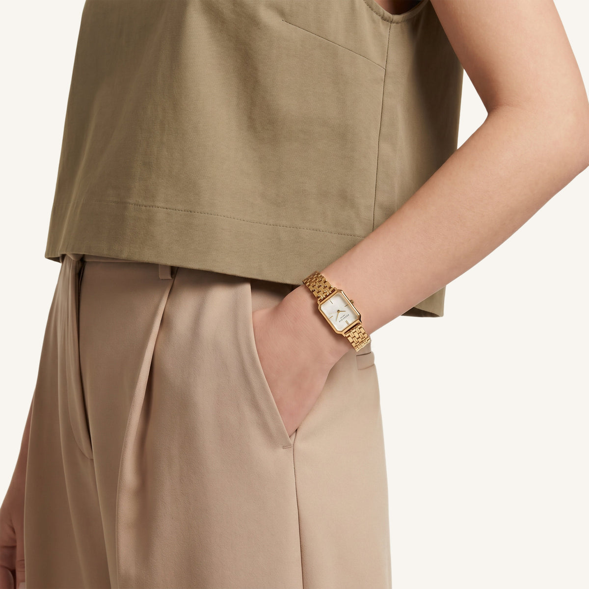 Gold-tone octagon watch worn with a hand in a trouser pocket