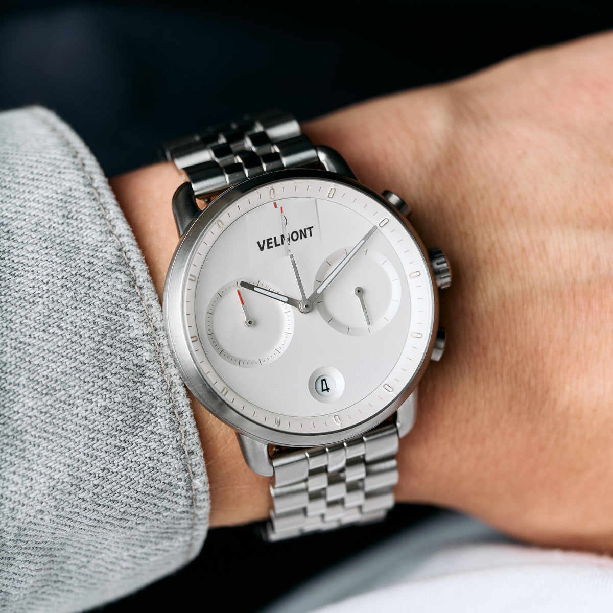 The silver-tone bracelet watch worn on a wrist next to a gray sweater.