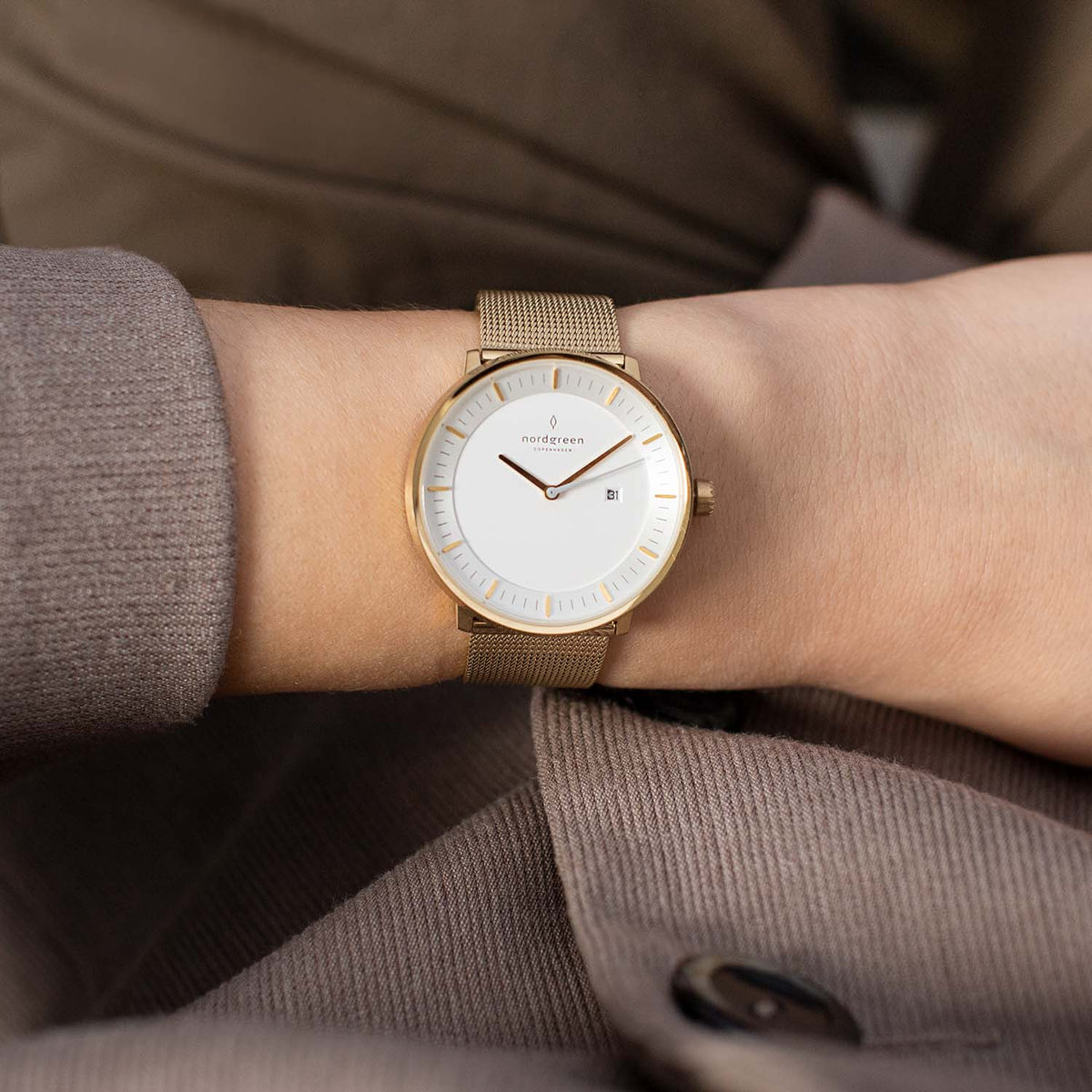Gold-tone mesh strap watch worn on the wrist