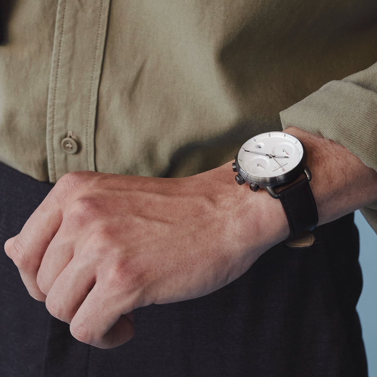The watch worn with an olive green button-up shirt and dark trousers.
