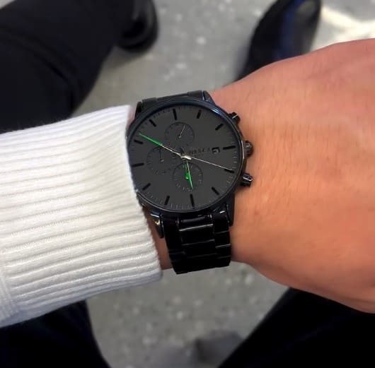Green accent watch on a wrist with white sweater