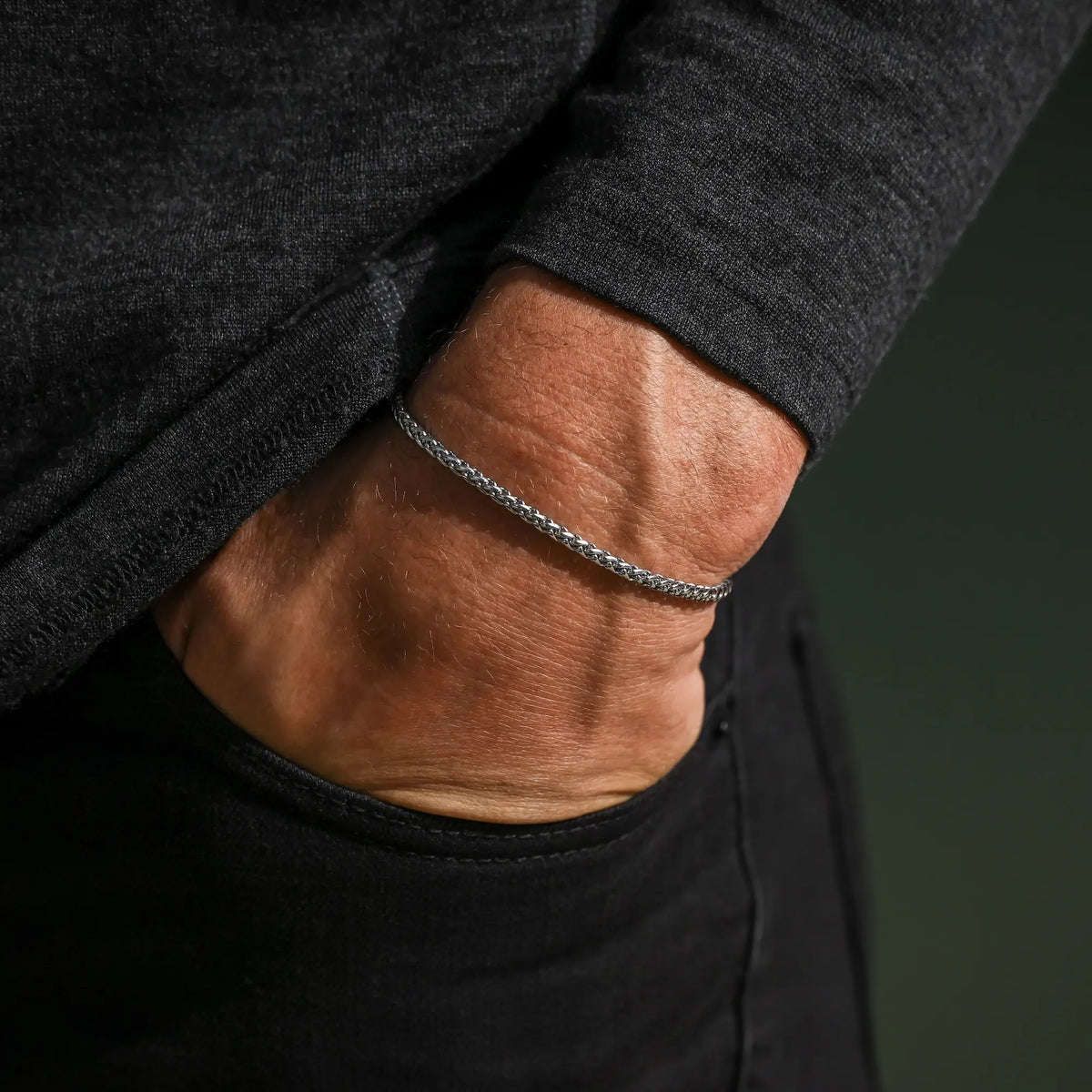 Wheat chain bracelet on a wrist resting in a pocket