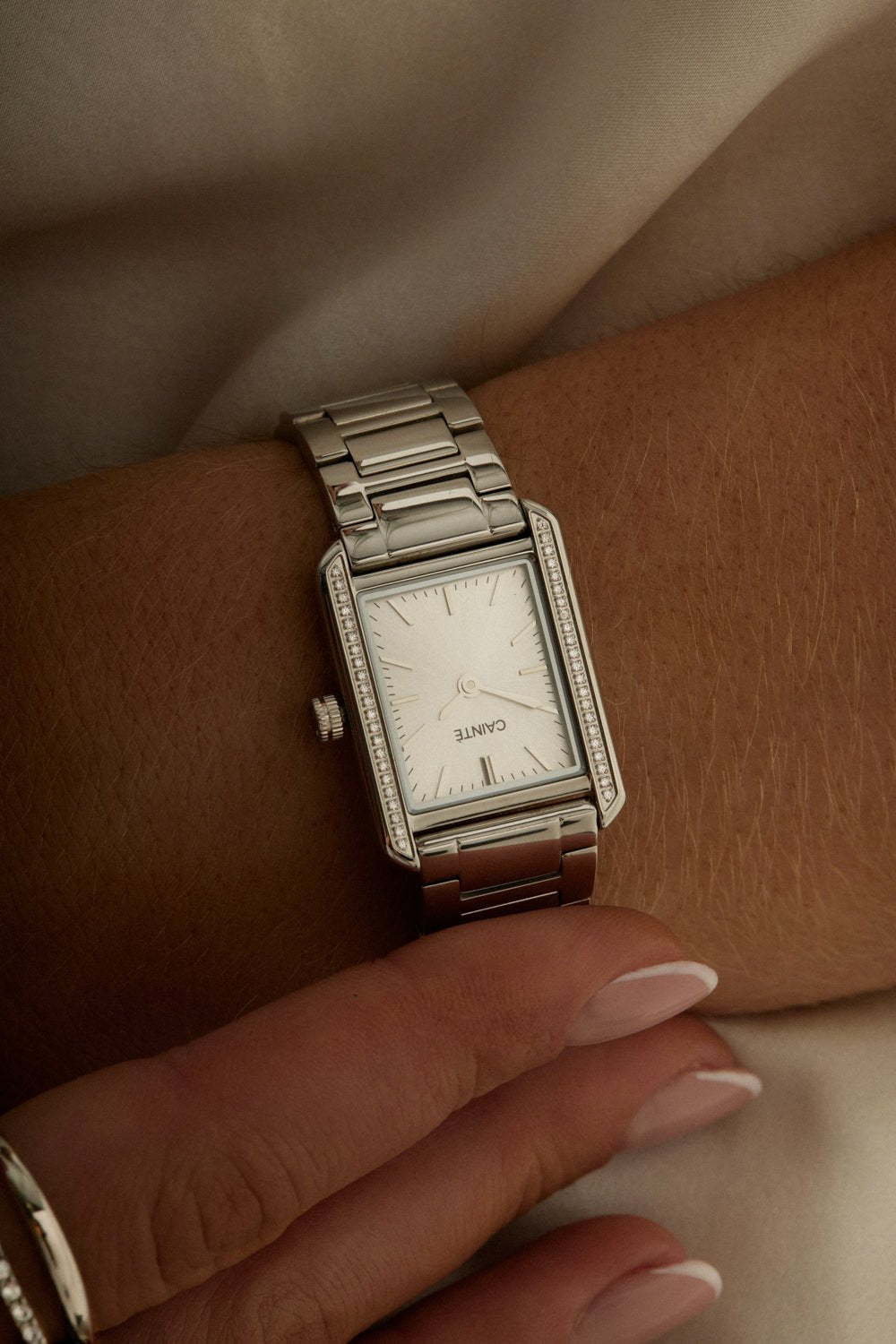Hands crossed over a white top, watch on the wrist