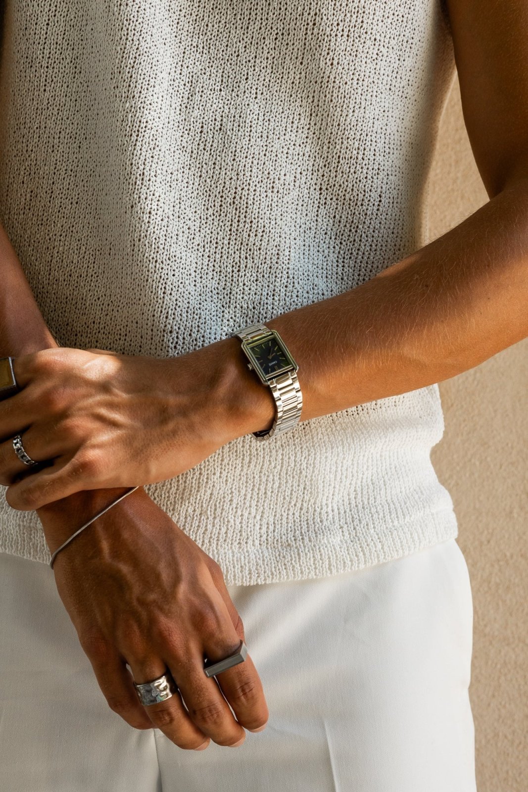 Arms crossed over a knit top, watch on the wrist