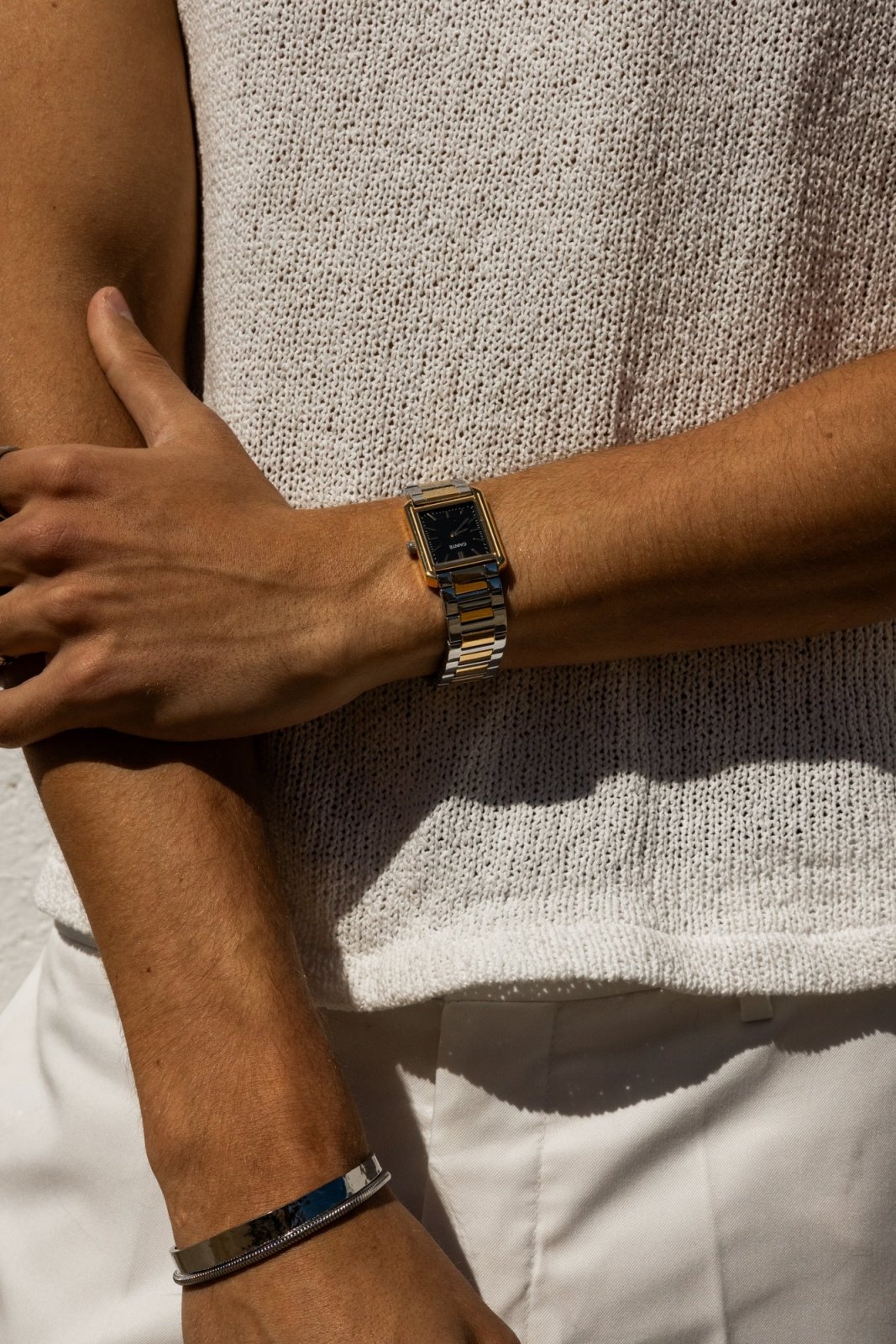 Arms crossed over a knit top, watch on the wrist