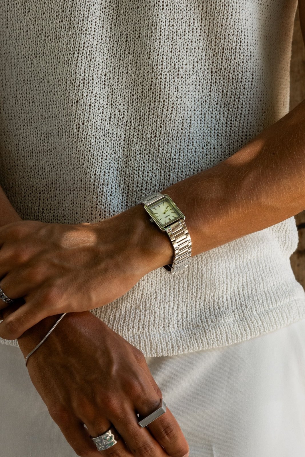 Arms crossed over a knit top, watch on the wrist