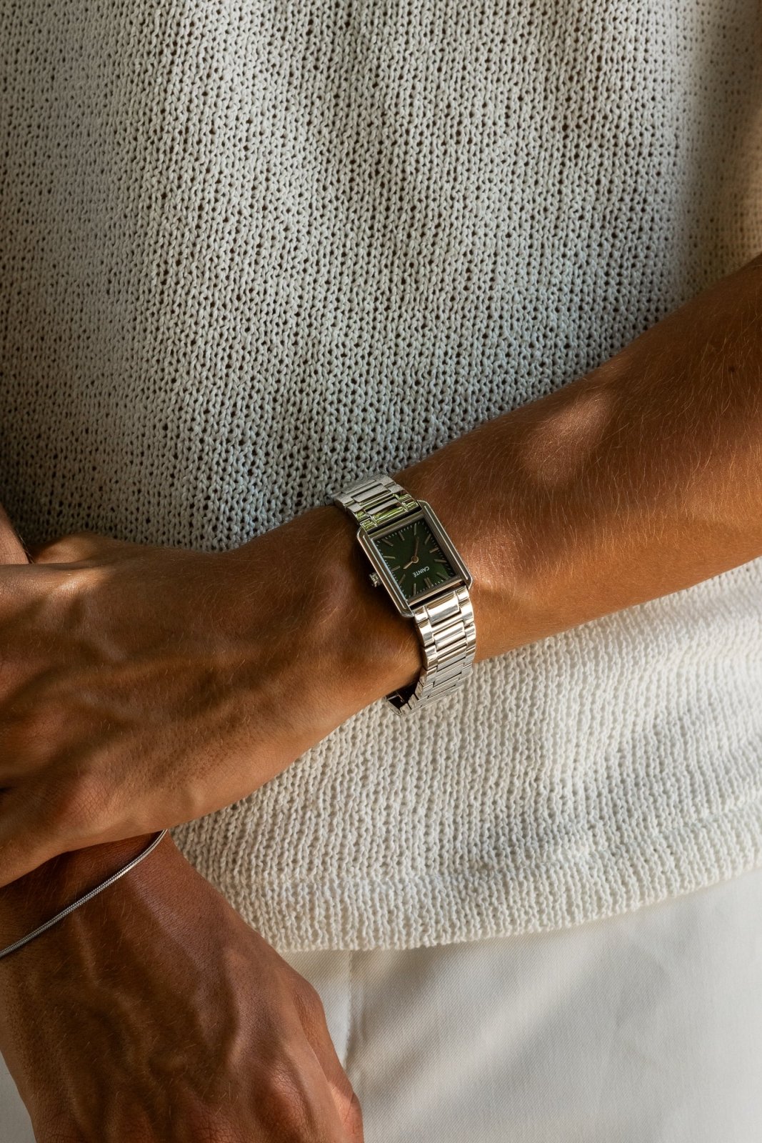 Wrist in a knit sweater wearing the rectangular watch