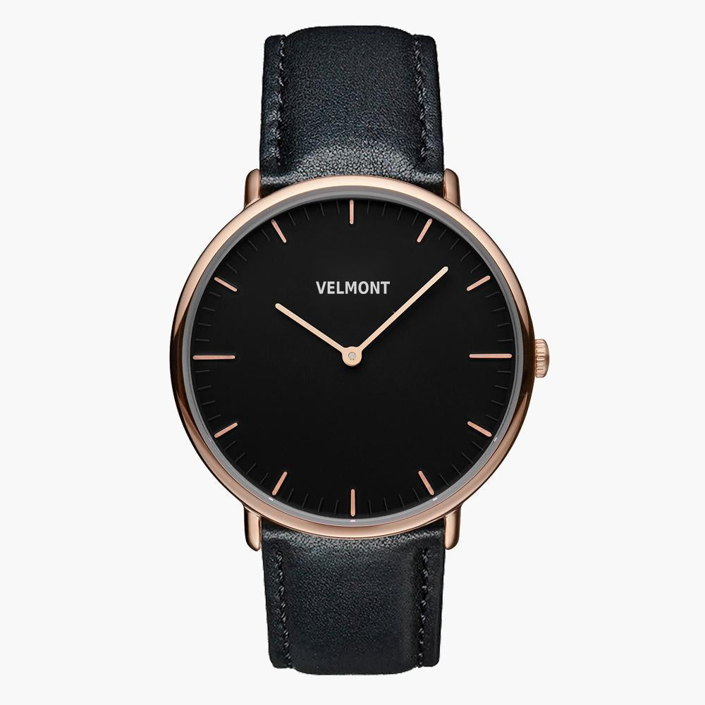 Watch with a black dial and rose gold-tone case on a black strap, shown from the front.