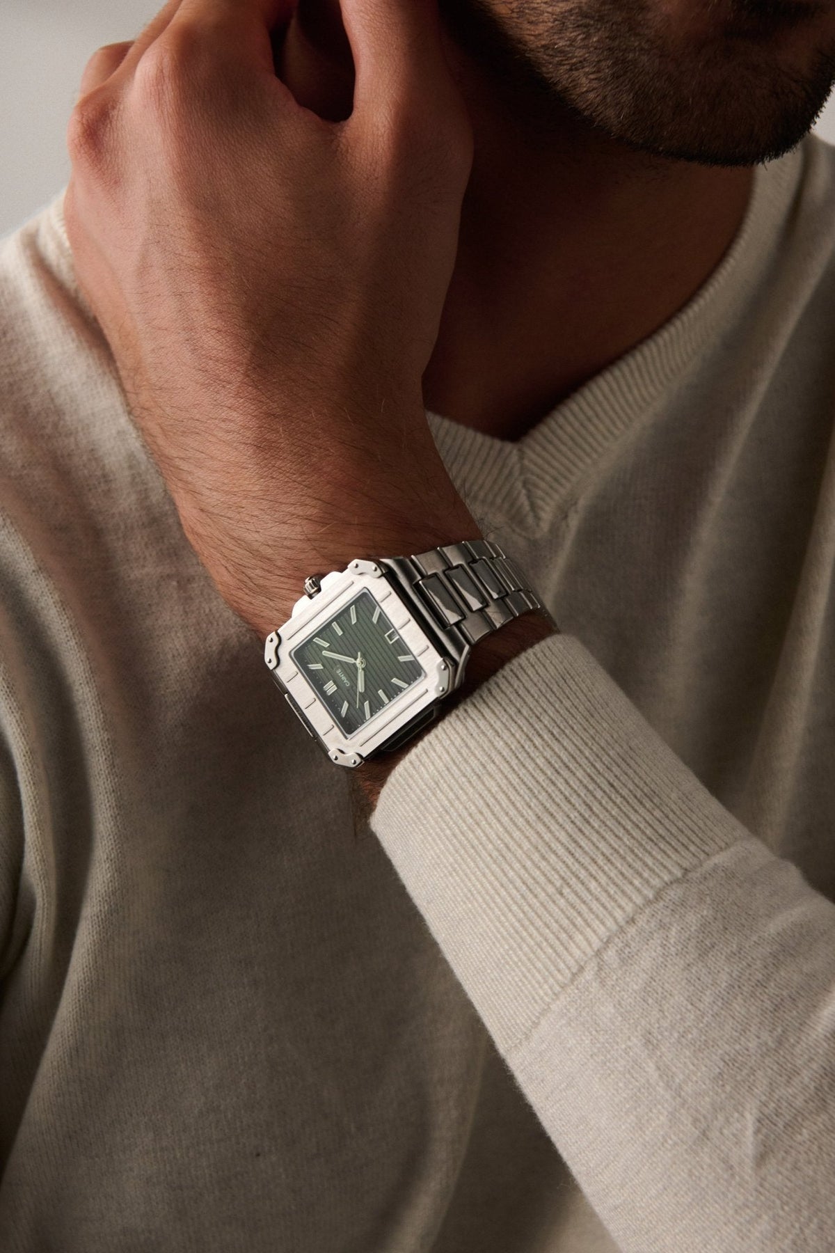 Square watch on a wrist in a cream sweater
