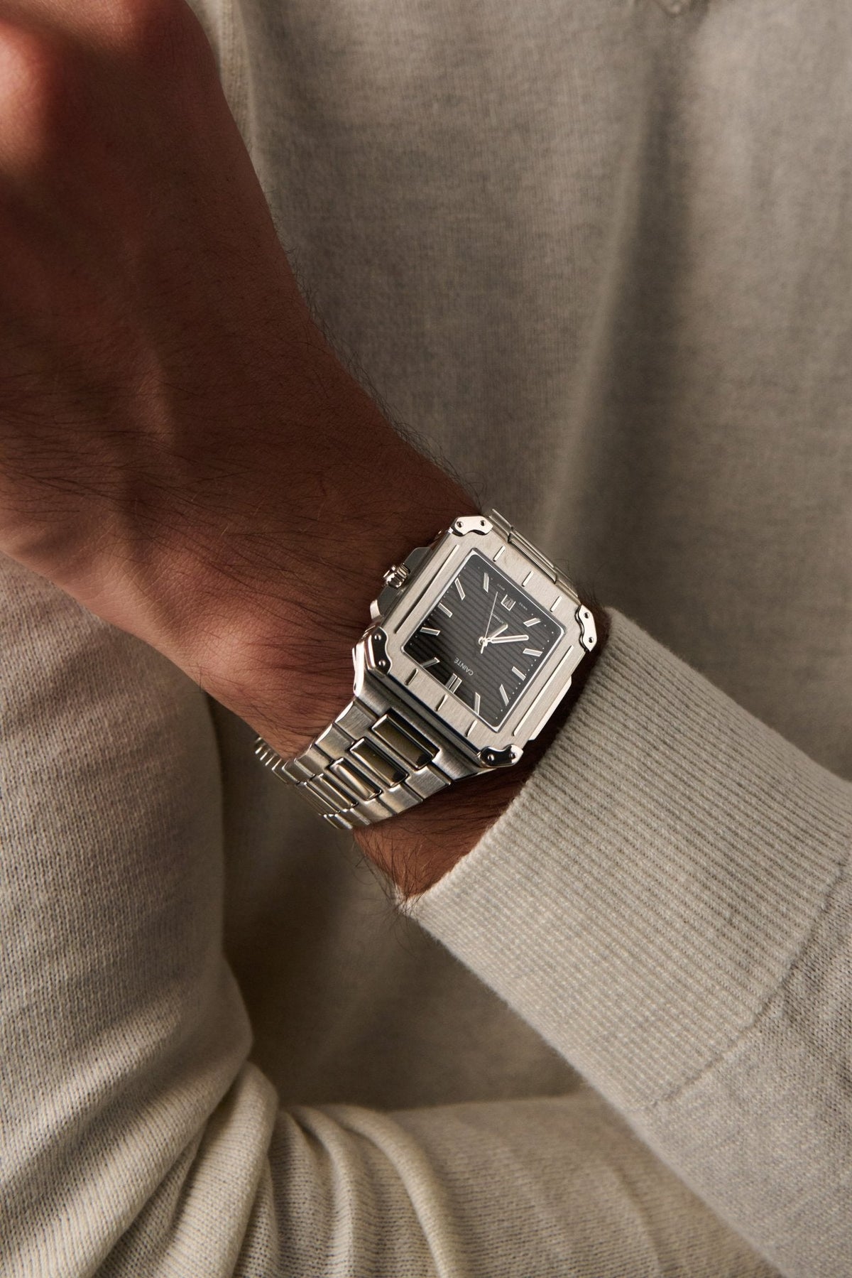 Square watch on a wrist in a cream sweater