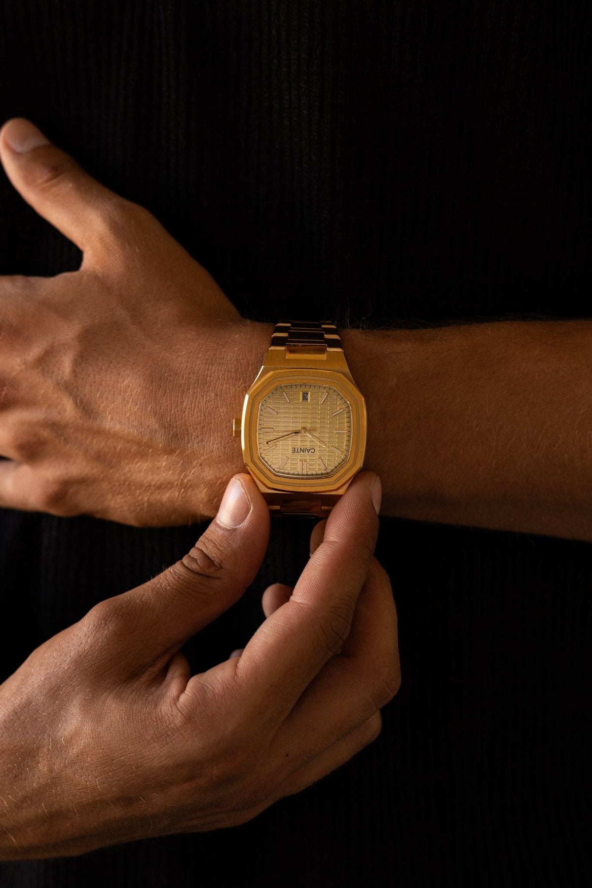 Hand adjusting the watch over a black shirt
