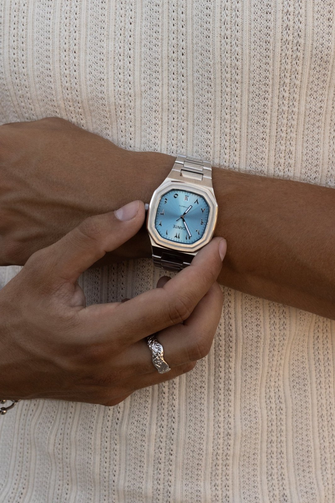 Hand adjusting the watch over a ribbed knit tank