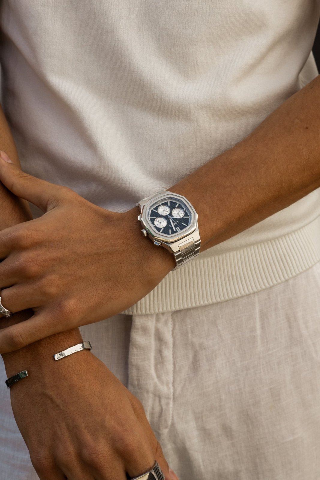 Arms crossed over a white T-shirt, watch on the wrist