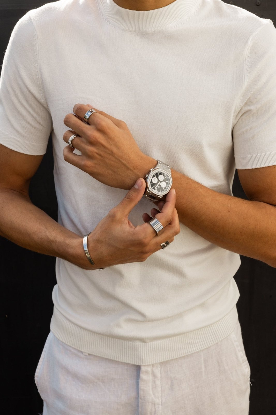 Fingers on the watch against a white tee