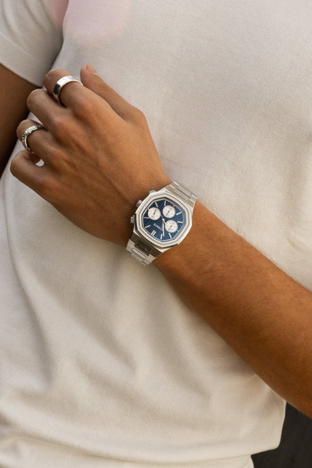 Watch on a wrist against a white T-shirt