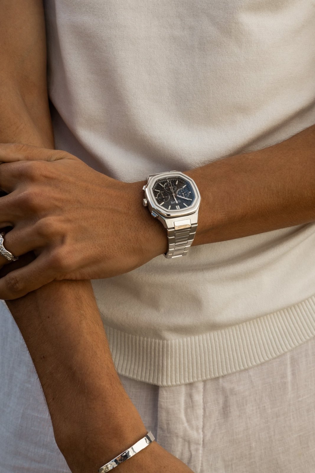 Arms crossed over a white T-shirt, watch on the wrist