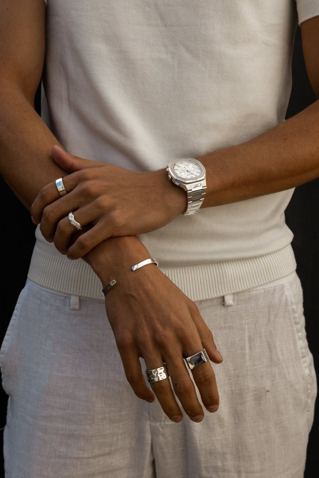 Arms folded in front of linen trousers, watch visible