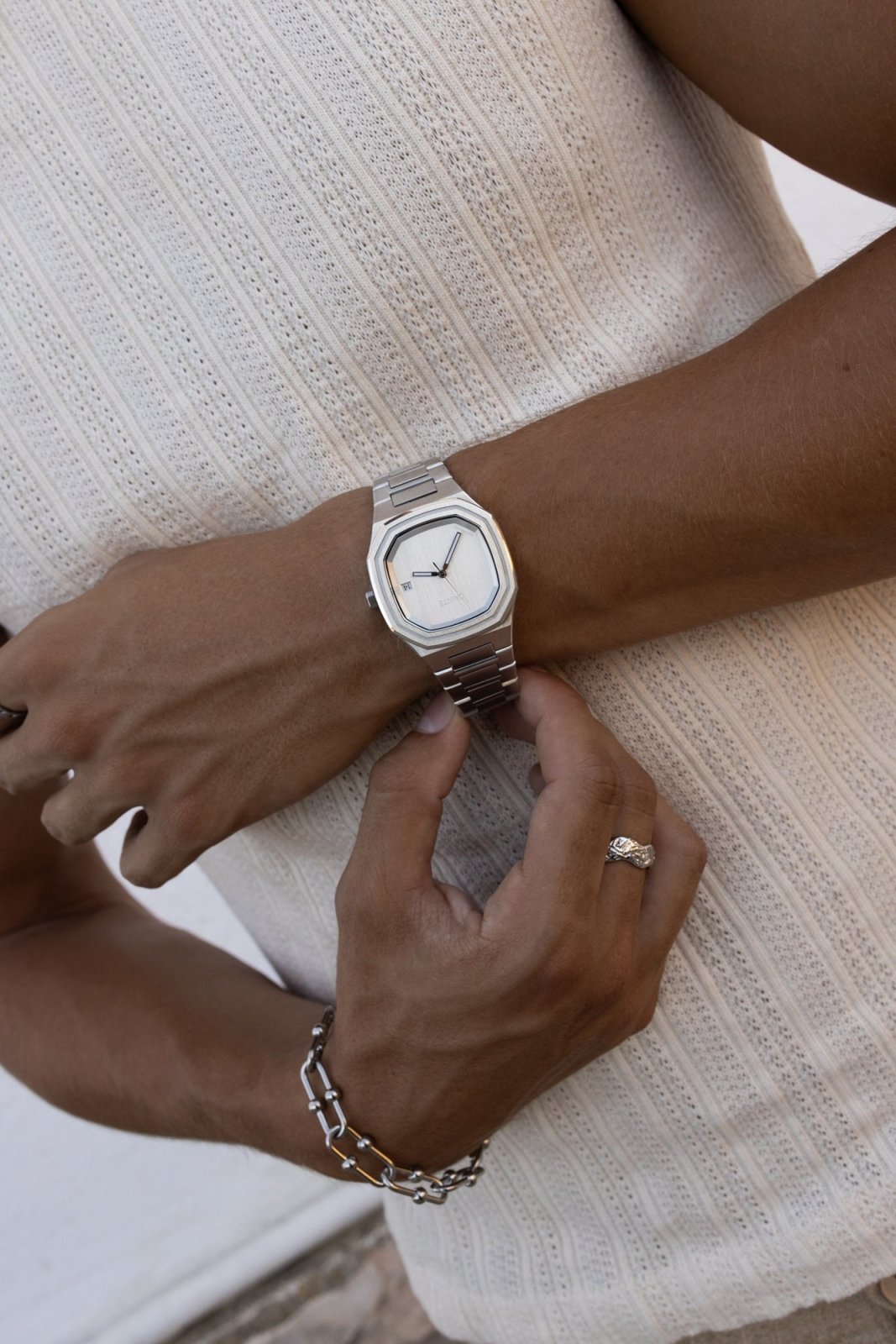 Hand adjusting the watch over a ribbed knit tank