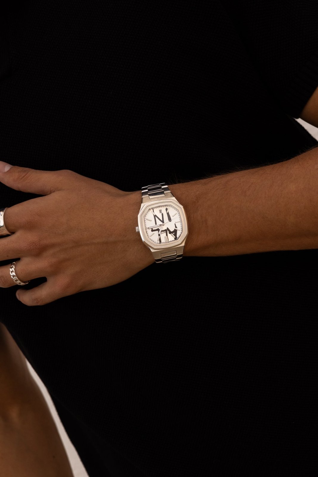 Watch on a wrist against a black top