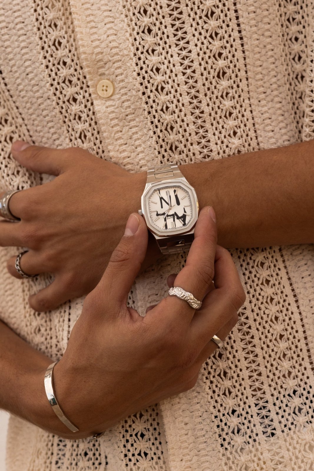 Hands adjusting the watch over a crochet shirt