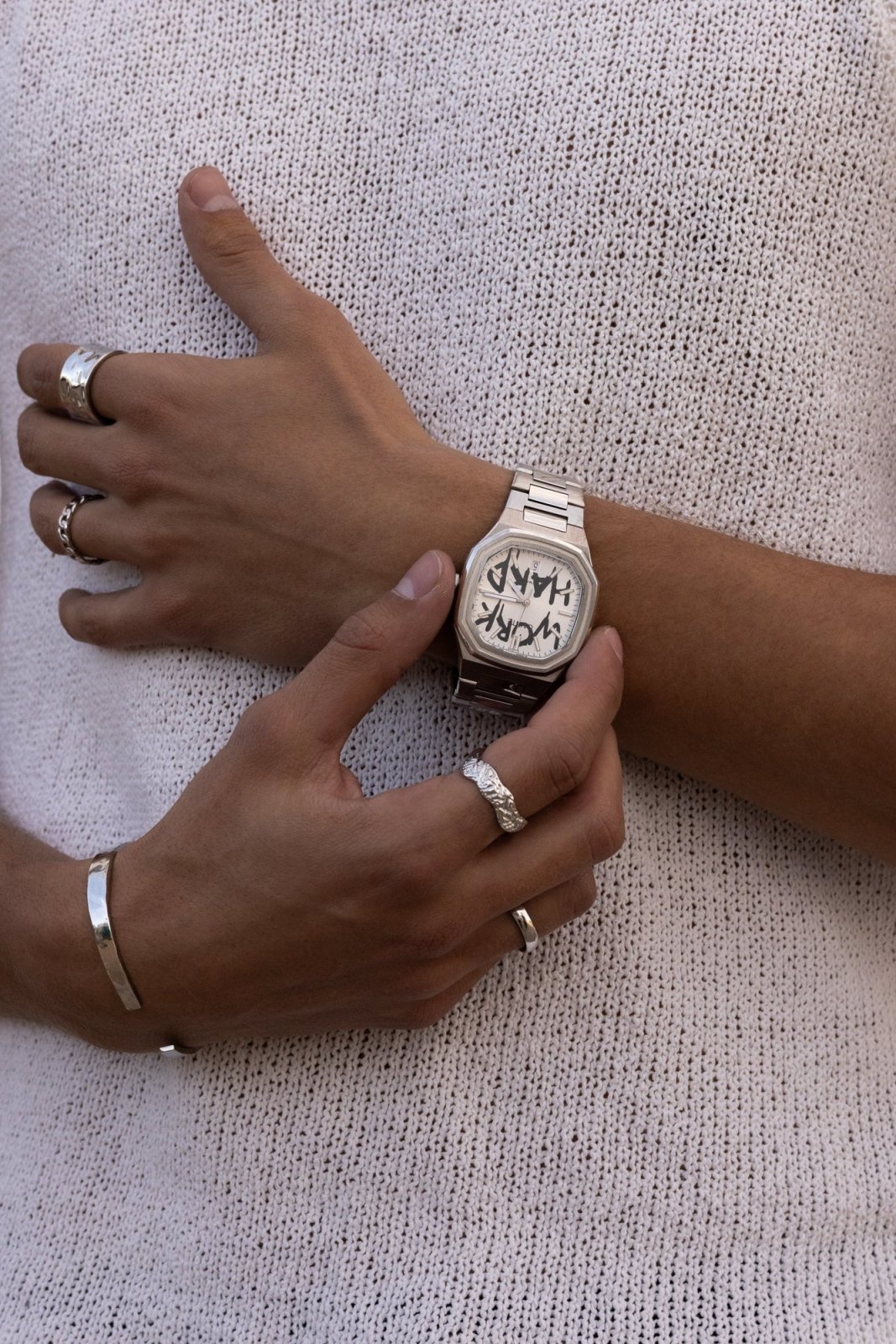 Hands adjusting the watch over a knit top