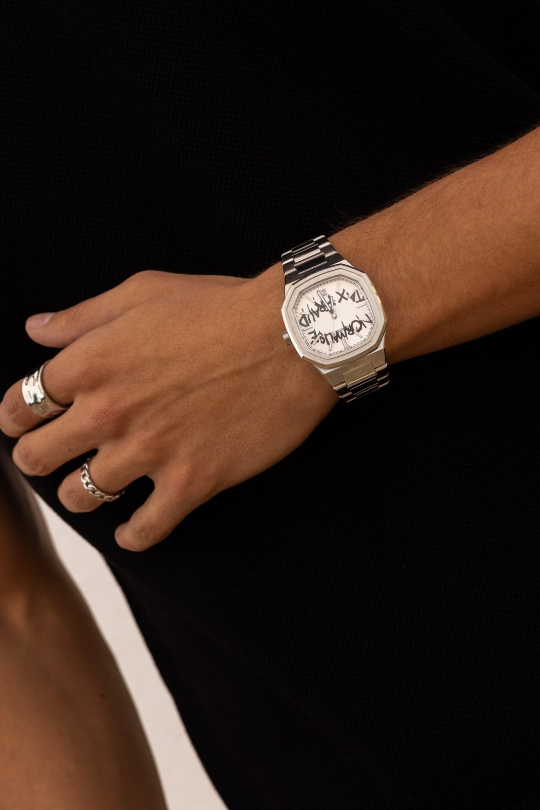 Watch on a wrist against a black top