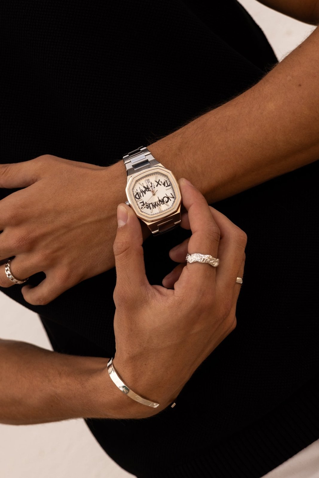 Hands adjusting the watch over a black top