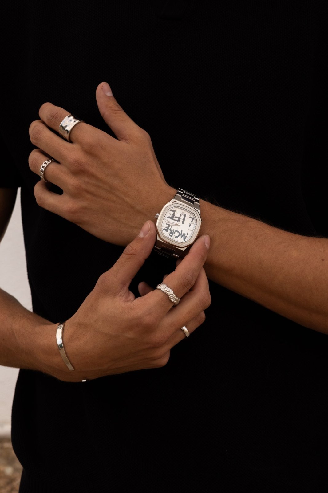 Hands adjusting the watch over a black top