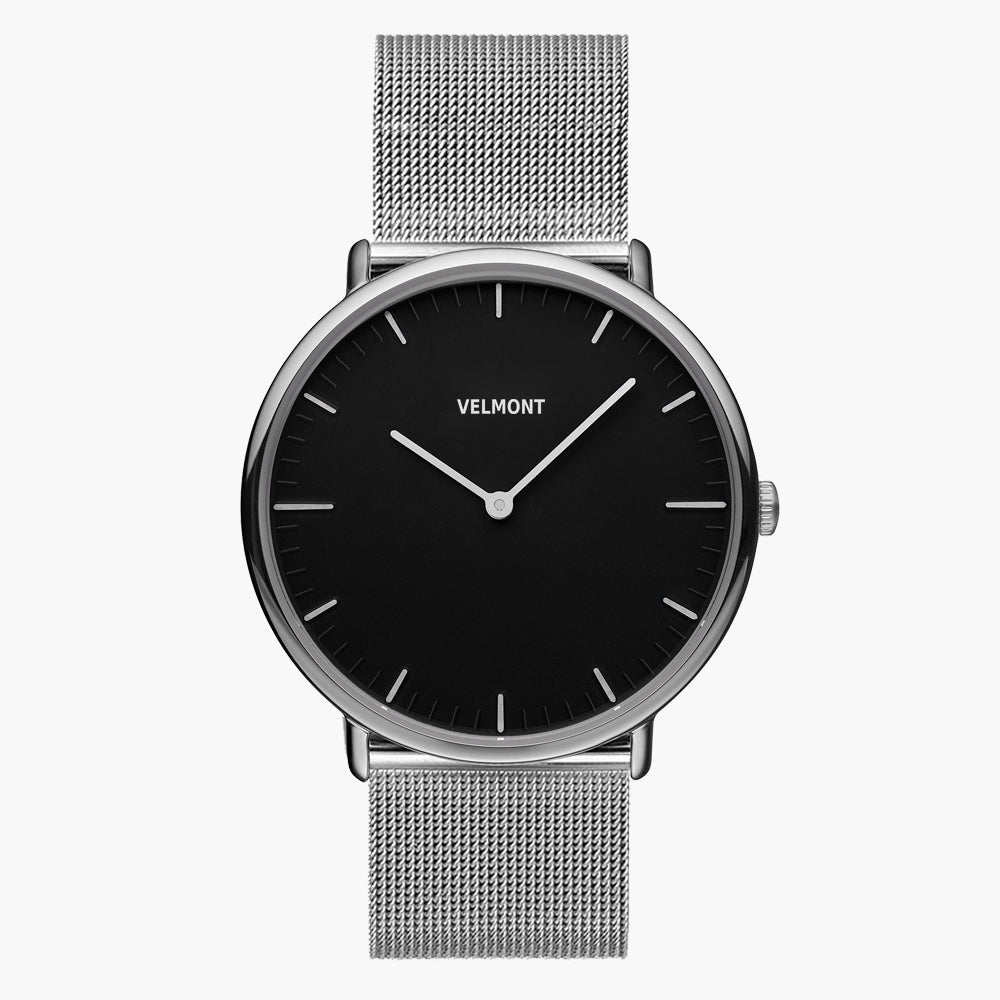 A black dial framed by a slim silver-tone case, set on a silver-tone mesh strap.