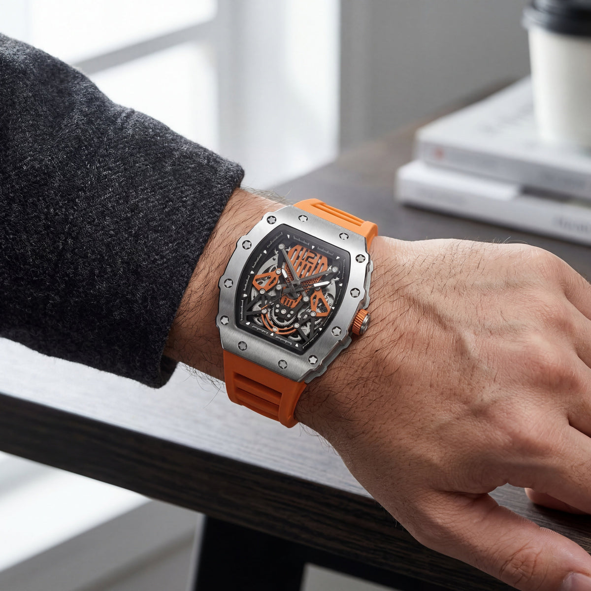 Orange skeleton watch on the wrist at a desk